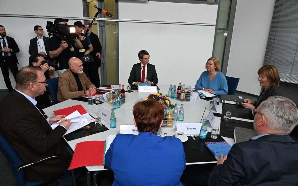 Journalisten nehmen mit Kamera und Mikrofon das Gespräch von 7 Verhandlungspartnern auf, die an einem runden Tisch sitzen. Darunter Bundesministerin des Innern Nancy Faeser.